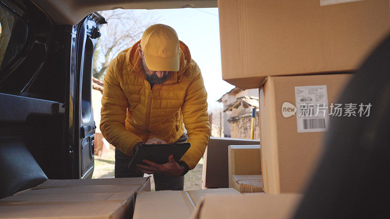 Courier with tablet checks postal parcels for delivery.